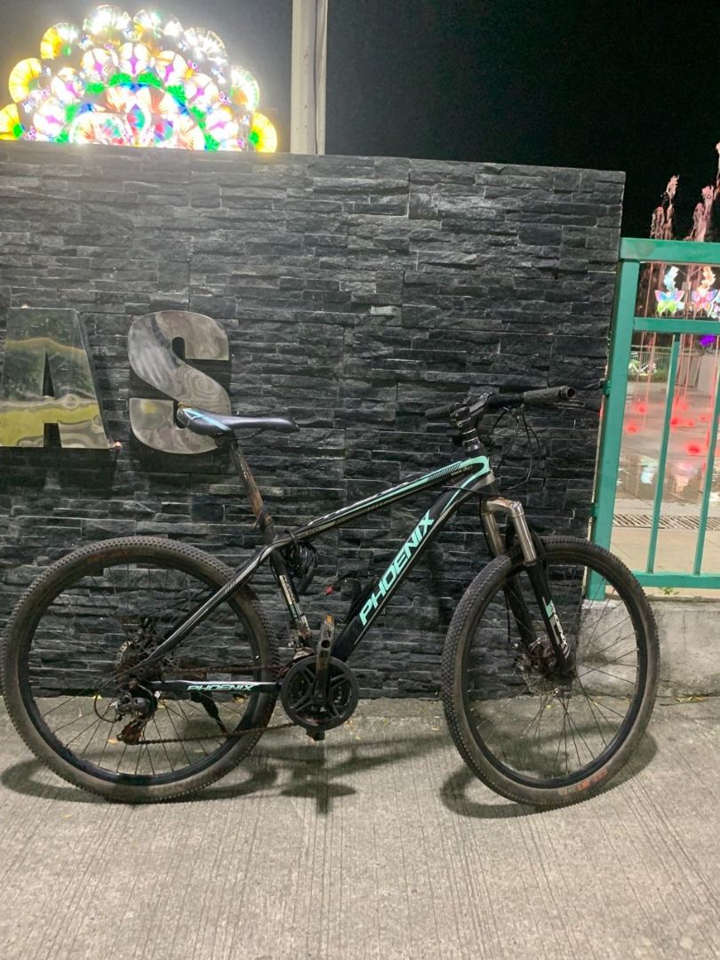 Phoenix Mountain Bike (Category: Bicycles) located in Dasmarinas. Submitted by irism7guel (Listing ID 1467503159, Image 2). Description: Fast sale (para mabenta agad) - Brand: Phoenix - Model: Hardtail MTB (SuperX / New Design) - Fork: FHS300 - 3×7 speed - Disc brakes - Black + teal/mint accents - Still working well, ready to ride. - second hand Freebies: - Bike tail red light - Bottle cage - Bicycle phone holder (Willing to negotiate. pick-up on