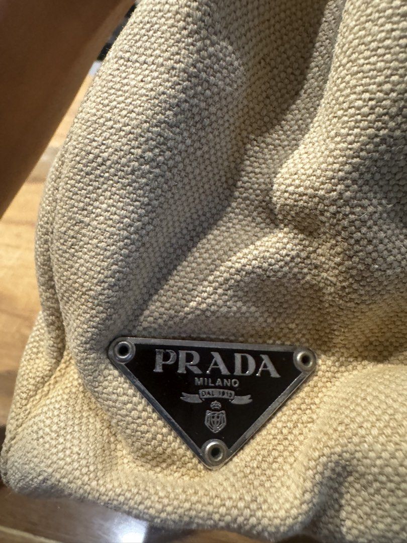 Prada Beige Canvas Shoulder Bag (Category: Luxury Bags & Wallets) located in Paranaque City. Submitted by prelovedfrompat (Listing ID 1467444479, Image 2). Description: - Brand: Prada - Color: Beige canvas with dark brown leather handles - Hardware/Logo: Iconic triangular metal logo plaque - Closure: Simple and secure zip closure - Structure: Structured shape with woven fabric texture - Style: Classic designer piece, very easy to match with daily