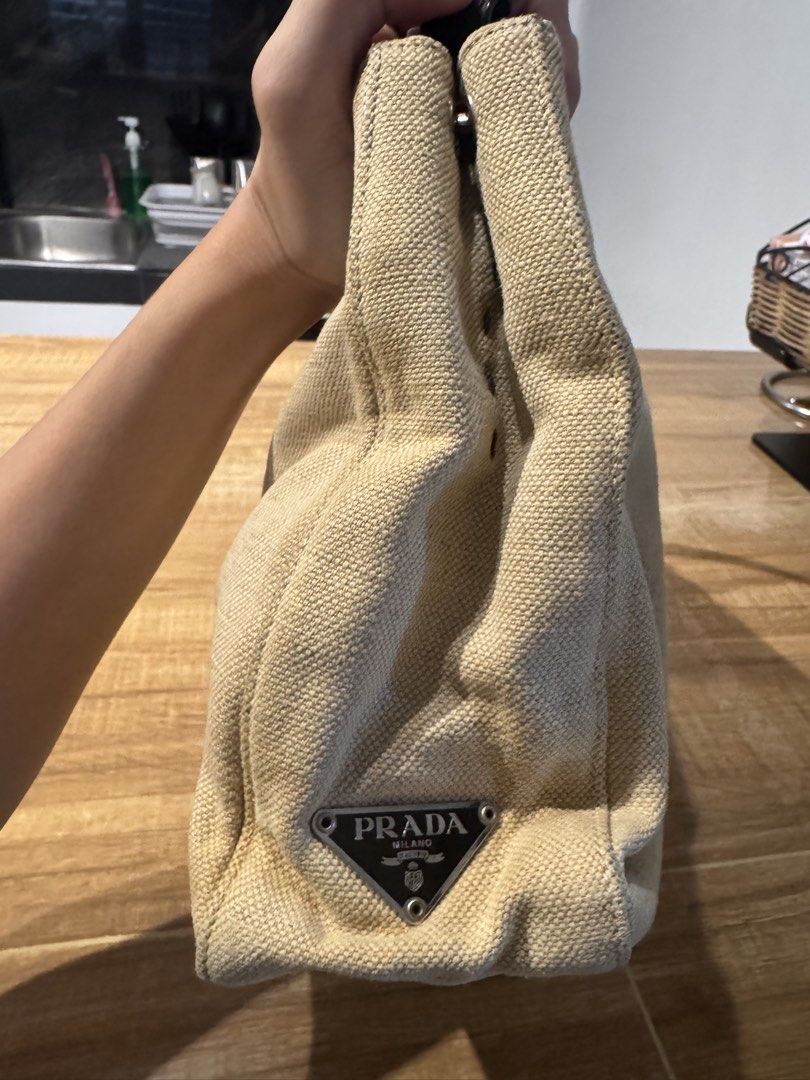 Prada Beige Canvas Shoulder Bag (Category: Luxury Bags & Wallets) located in Paranaque City. Submitted by prelovedfrompat (Listing ID 1467444479, Image 1). Description: - Brand: Prada - Color: Beige canvas with dark brown leather handles - Hardware/Logo: Iconic triangular metal logo plaque - Closure: Simple and secure zip closure - Structure: Structured shape with woven fabric texture - Style: Classic designer piece, very easy to match with daily