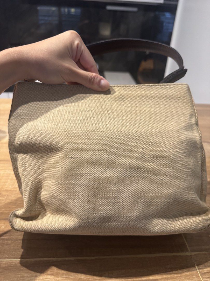 Prada Beige Canvas Shoulder Bag (Category: Luxury Bags & Wallets) located in Paranaque City. Submitted by prelovedfrompat (Listing ID 1467444479, Image 3). Description: - Brand: Prada - Color: Beige canvas with dark brown leather handles - Hardware/Logo: Iconic triangular metal logo plaque - Closure: Simple and secure zip closure - Structure: Structured shape with woven fabric texture - Style: Classic designer piece, very easy to match with daily