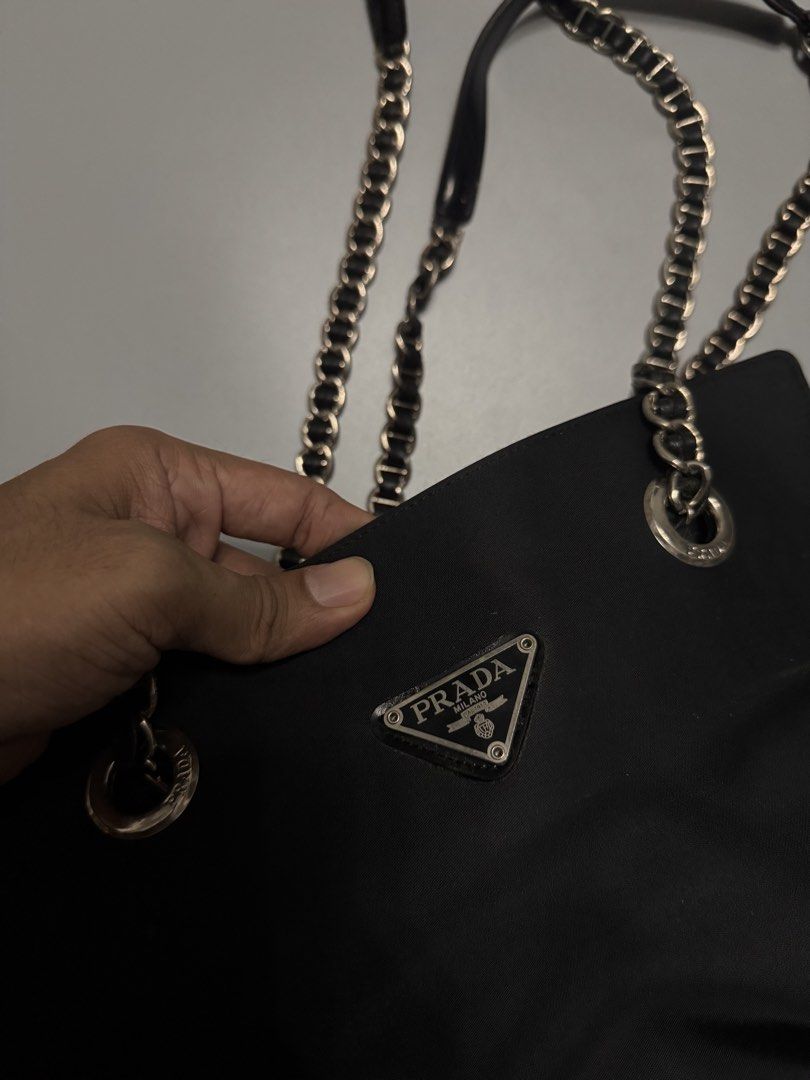 Prada Black Nylon Chain Shoulder Bag (Category: Luxury Bags & Wallets) located in Alaminos. Submitted by outfitcheck.ph (Listing ID 1467486112, Image 2). Description: - Prada shoulder bag in classic black nylon - Silver-tone chain straps featuring comfortable leather shoulder guards - Iconic enamel triangle logo on the front - Stylish branded metal grommets on top - Structured shape with a dark interior lining - Practical daily size: easily fits 