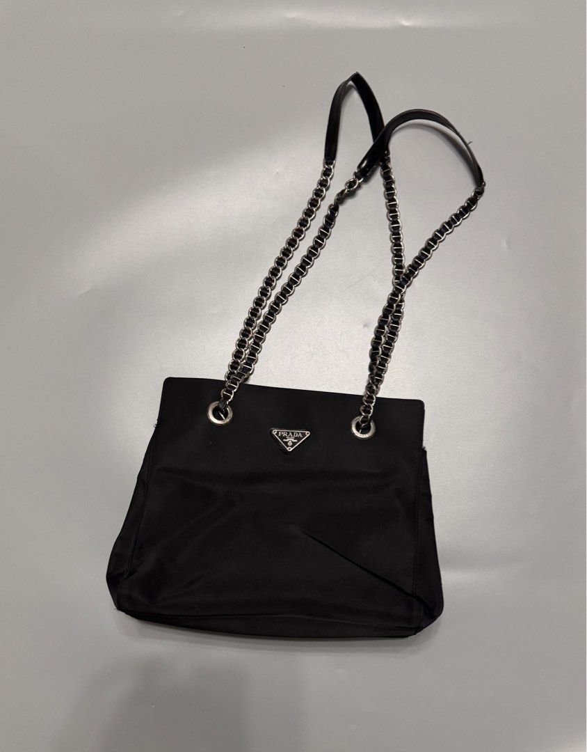 Prada Black Nylon Chain Shoulder Bag (Category: Luxury Bags & Wallets) located in Alaminos. Submitted by outfitcheck.ph (Listing ID 1467486112, Image 1). Description: - Prada shoulder bag in classic black nylon - Silver-tone chain straps featuring comfortable leather shoulder guards - Iconic enamel triangle logo on the front - Stylish branded metal grommets on top - Structured shape with a dark interior lining - Practical daily size: easily fits 