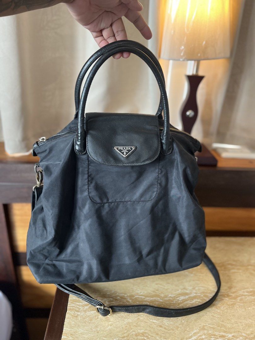 Prada Black Nylon Flap Handbag with Crossbody Strap (Category: Luxury Bags & Wallets) located in Tacloban City. Submitted by luxbag_phhh (Listing ID 1467593855, Image 1). Description: - Prada nylon handbag in classic black - Twin leather handles and matching adjustable shoulder strap included - Front flap pocket accented with the signature triangular logo plaque - Secure top zip closure with gold-tone hardware - Lightweight, roomy, and ideal for 