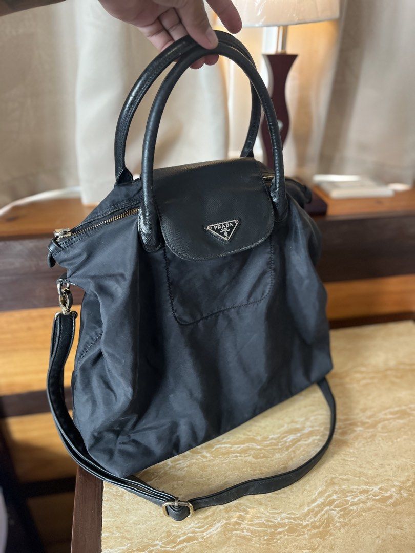Prada Black Nylon Flap Handbag with Crossbody Strap (Category: Luxury Bags & Wallets) located in Tacloban City. Submitted by luxbag_phhh (Listing ID 1467593855, Image 2). Description: - Prada nylon handbag in classic black - Twin leather handles and matching adjustable shoulder strap included - Front flap pocket accented with the signature triangular logo plaque - Secure top zip closure with gold-tone hardware - Lightweight, roomy, and ideal for 