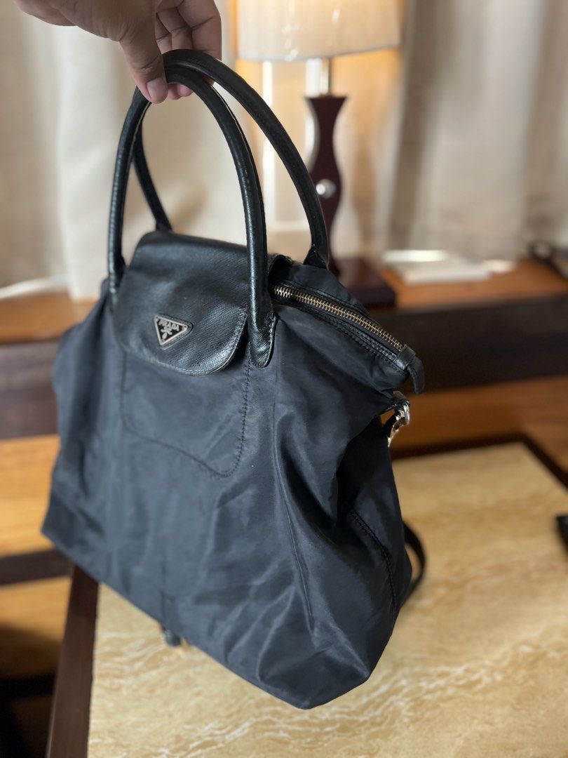Prada Black Nylon Flap Handbag with Crossbody Strap (Category: Luxury Bags & Wallets) located in Tacloban City. Submitted by luxbag_phhh (Listing ID 1467593855, Image 3). Description: - Prada nylon handbag in classic black - Twin leather handles and matching adjustable shoulder strap included - Front flap pocket accented with the signature triangular logo plaque - Secure top zip closure with gold-tone hardware - Lightweight, roomy, and ideal for 