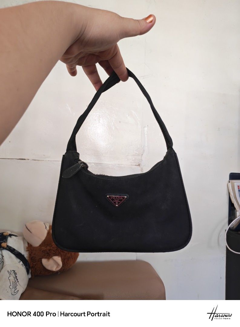 Prada Black Nylon Mini Hobo Bag (Category: Luxury Bags & Wallets) located in Manila. Submitted by cleverwhale_45b7bc (Listing ID 1467375015, Image 1). Description: - Prada nylon shoulder bag in timeless black - Features the iconic enamel triangle logo on the front - Secure zip-top closure - Note on condition: Visible tarnishing and oxidation on the hardware/zipper, plus dust accumulation reflecting its pre-loved, vintage nature - Perfect everyday