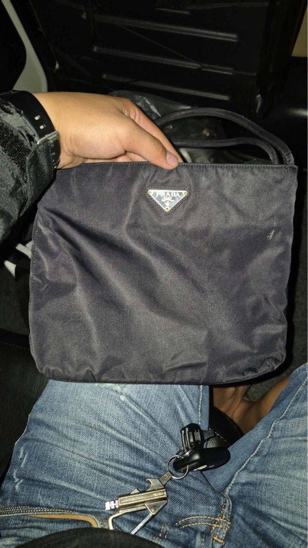 Prada Nylon Black Shoulder Bag (Category: Luxury Bags & Wallets) located in Tabuk. Submitted by collectors_thrift_shop (Listing ID 1467424029, Image 1). Description: - Authentic black Prada nylon shoulder bag - Iconic enamel triangle logo on the front - Lightweight design with classic minimalist aesthetic - Double shoulder straps and secure top zip closure - Interior zip pocket with signature logo jacquard lining - Condition: Normal signs of prev