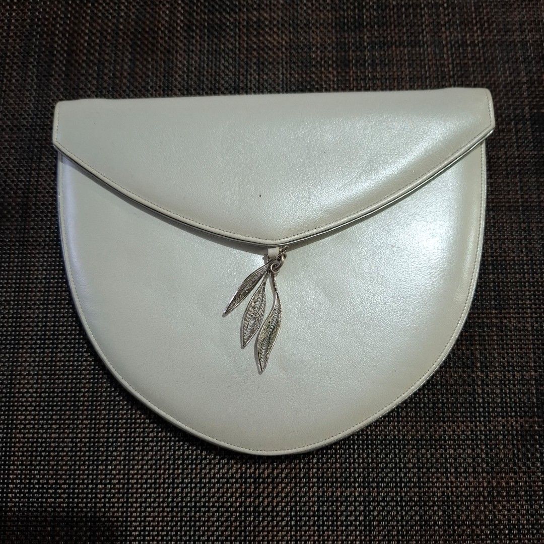 Queenly White Semi-Circle Clutch Bag with Leaf Charm (Category: Clutches) located in Don Carlos. Submitted by PphiXi_Finds (Listing ID 1467439199, Image 1). Description: - Brand: Queenly - Style: White semi-circle clutch bag with front flap - Versatile: Includes a removable metal chain strap for shoulder or hand carry - Details: Magnetic closure, black inner lining, and a cute dangling silver leaf charm - Condition: Minor wear visible near the in