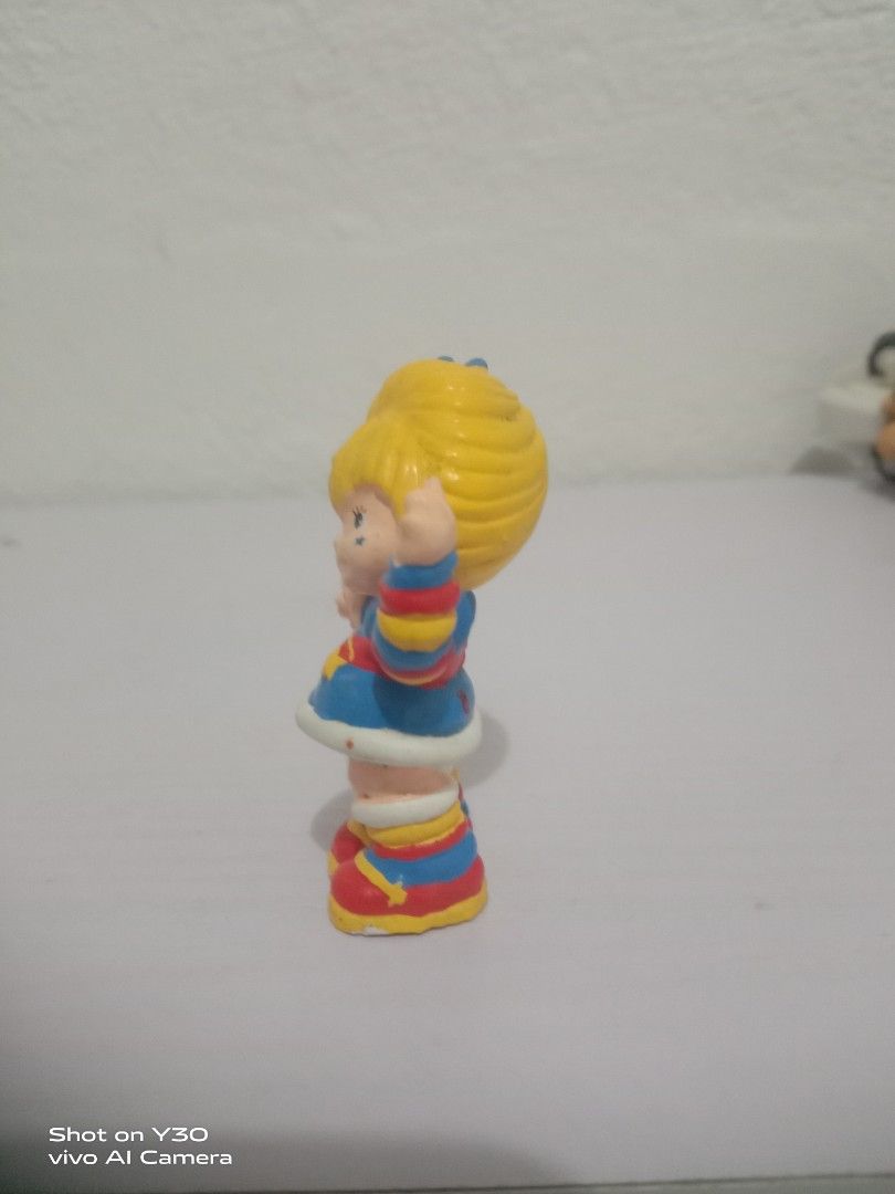 Rainbow Brite (Category: Figurines & Statues) located in Orani. Submitted by rodel1991 (Listing ID 1467373897, Image 3). Description: - Retro plastic toy figure of a smiling blonde girl - Waving pose with one hand up - Colorful blue, red, and yellow outfit with striped sleeves and socks - Painted blue eyes and a cute star mark on the cheek - Bright primary color design, perfect for collectors.