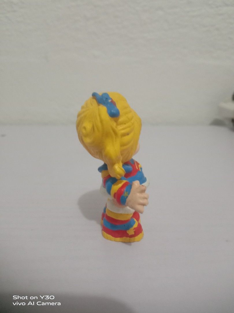 Rainbow Brite (Category: Figurines & Statues) located in Orani. Submitted by rodel1991 (Listing ID 1467373897, Image 2). Description: - Retro plastic toy figure of a smiling blonde girl - Waving pose with one hand up - Colorful blue, red, and yellow outfit with striped sleeves and socks - Painted blue eyes and a cute star mark on the cheek - Bright primary color design, perfect for collectors.