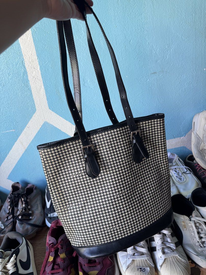 Ralph Lauren Houndstooth Tote Bag (Category: Tote Bags) located in Manila. Submitted by meegy (Listing ID 1467427130, Image 2). Description: - Brand: Ralph Lauren - Design: Classic black and white houndstooth pattern with black leather trim - Straps: Sturdy black leather straps with buckle adjustments for custom fit - Hardware: Silver-tone hardware featuring a zippered metal brand plaque on the front - Interior/Capacity: Clean, structured, and sp