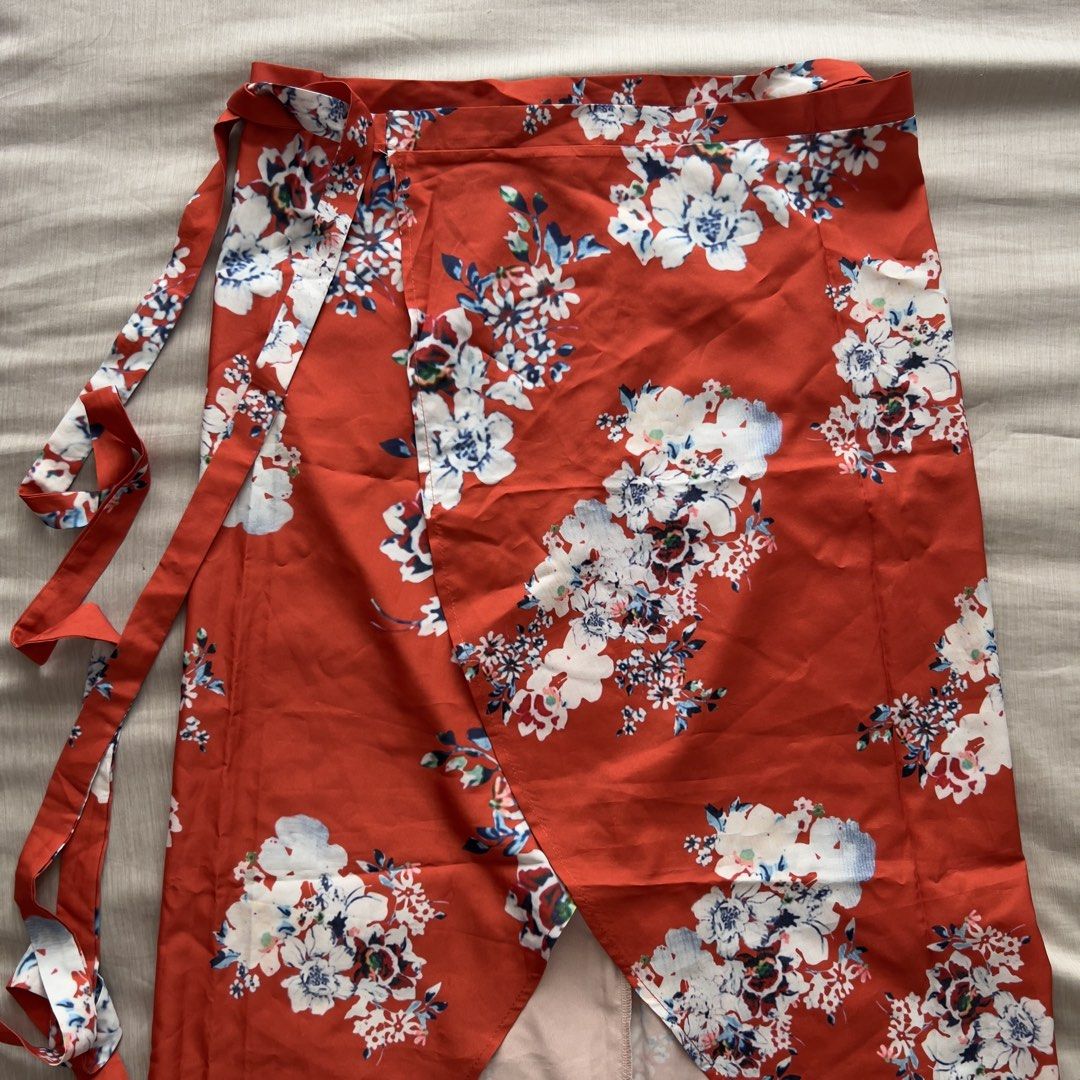 Red Floral Wrap Beach Skirt (Category: Skirts) located in Pasig City. Submitted by jenscloset86 (Listing ID 1467397167, Image 2). Description: Size: Free Size • Red with white and blue floral print • Midi length with a stylish curved hem • 100% lightweight and flowy polyester • Adjustable self-tie waist straps • Perfect for casual days, beach trips, or weekend dates Measurement (in inches): Length: 39” Waist: 25-30” adjustable tie.
