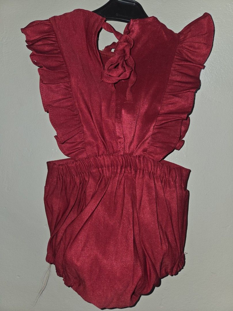 Red ruffled romper playsuit with tie back (Category: Babies & Kids Fashion) located in Quezon City. Submitted by klarebear15 (Listing ID 1467583126, Image 2). Description: - Color: Deep red - Design: Sweet ruffle front edges with a matching tie-back strap - Fit: Comfortable elasticated waist with a pleated lower section - Fabric: Lightweight and breezy for warm days - Condition: Pre-loved, part of a wardrobe clearout.