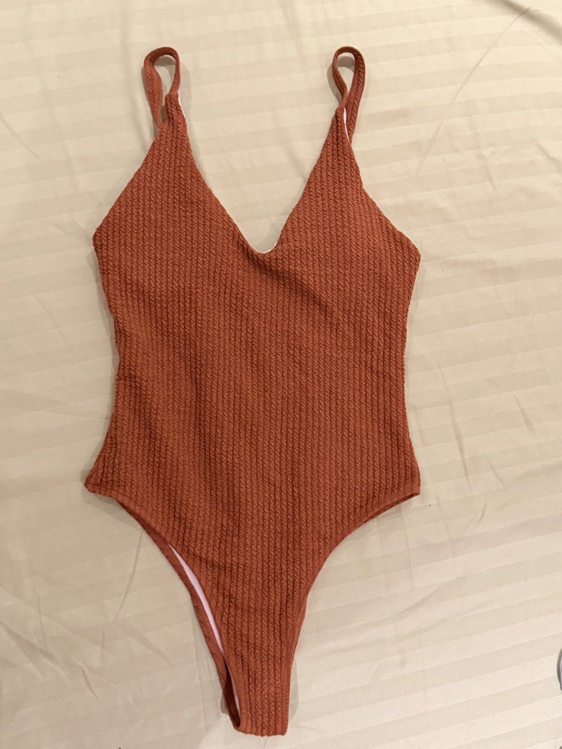 Rust Orange Crinkle One-Piece Swimsuit with Crossback Straps (Category: Bikinis & Swimsuits) located in Quezon City. Submitted by caathhx_ (Listing ID 1467510759, Image 1). Description: - Color: Rich rust orange with light pink lining - Material: Textured crinkle fabric - Design: Deep v-neck front and back, high-cut leg - Details: Adjustable shoulder straps with cute crisscross back - Perfect for: Beach trips and pool days.