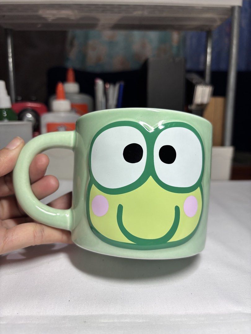 Sanrio Keroppi Ceramic Mug Paladone (Category: Coffee & Tea Tableware) located in Baguio. Submitted by 21enygrace.ph (Listing ID 1467480871, Image 1). Description: - Authentic Paladone x Sanrio Keroppi mug (2025 copyright) - Design: Big Keroppi face on front, spelled-out name pattern on back - Colors: Light green handle, white interior - Flaw: Small paint chip near the bottom rim - Care: Hand wash recommended (dishwasher and microwave unsafe).