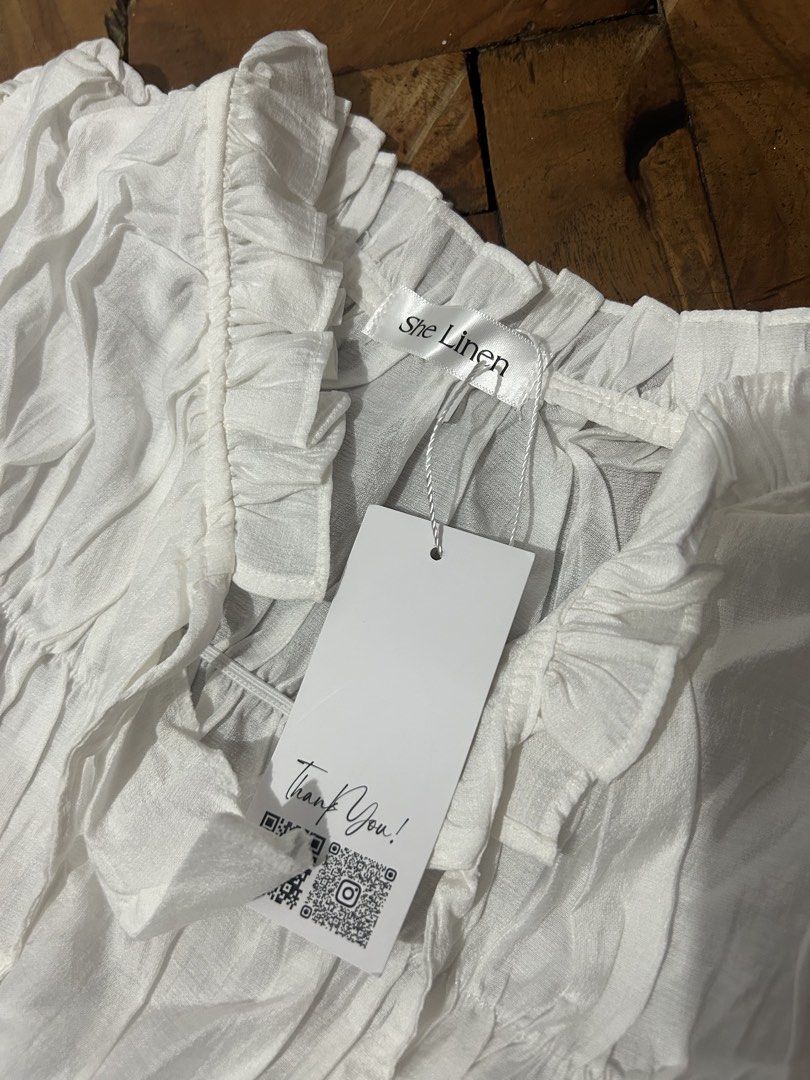 She Linen White Ruffle Blouse Tiered Top (Category: Blouses) located in Sorsogon. Submitted by jonacel (Listing ID 1467489796, Image 2). Description: - Brand: She Linen - Condition: Brand new with tag attached - Color: Classic White - Design: Tiered blouse with button front - Details: Ruffle collar and short flutter sleeves - Fabric: Lightweight with subtle texture - Styling: Versatile neutral piece, easy to match with jeans or skirts - fits smal