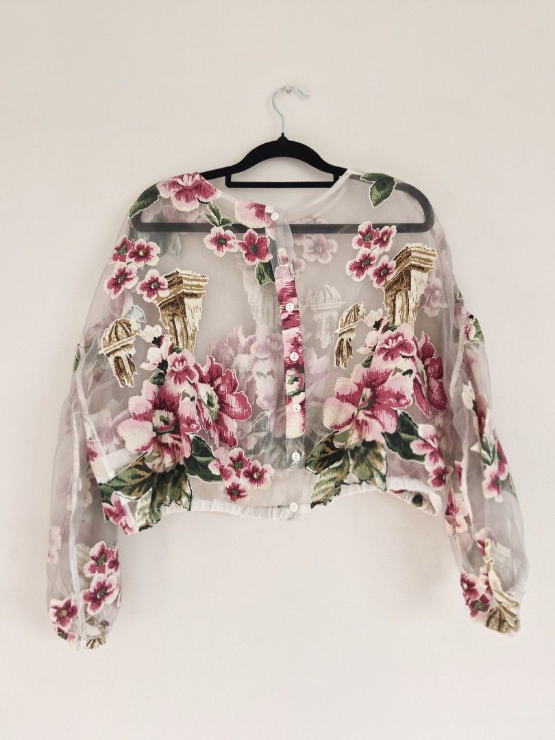 Sheer Floral Longsleeves Top (Category: Blouses) located in Manila. Submitted by unknowncloset (Listing ID 1467448820, Image 3). Description: - Sheer long-sleeve blouse with pink floral prints and architectural column graphics - Versatile design: can be worn frontwards or backwards - Cropped length with gathered elastic hem and cuffs - Made from a lightweight, breathable fabric - Features delicate floral appliques throughout for an extra touch of