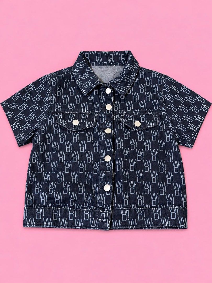 Short sleeve dark denim jacket all over monogram print (Category: Others Tops) located in Manila. Submitted by chelle_thrifted_shack (Listing ID 1467376888, Image 1). Description: - Color/Pattern: Dark blue with all-over white letter print - Style: Short-sleeve denim jacket with classic pointed collar - Details: Front button closure, two chest flap pockets with button snaps - Material: Structured denim with heavy contrasting stitching - Fit: True