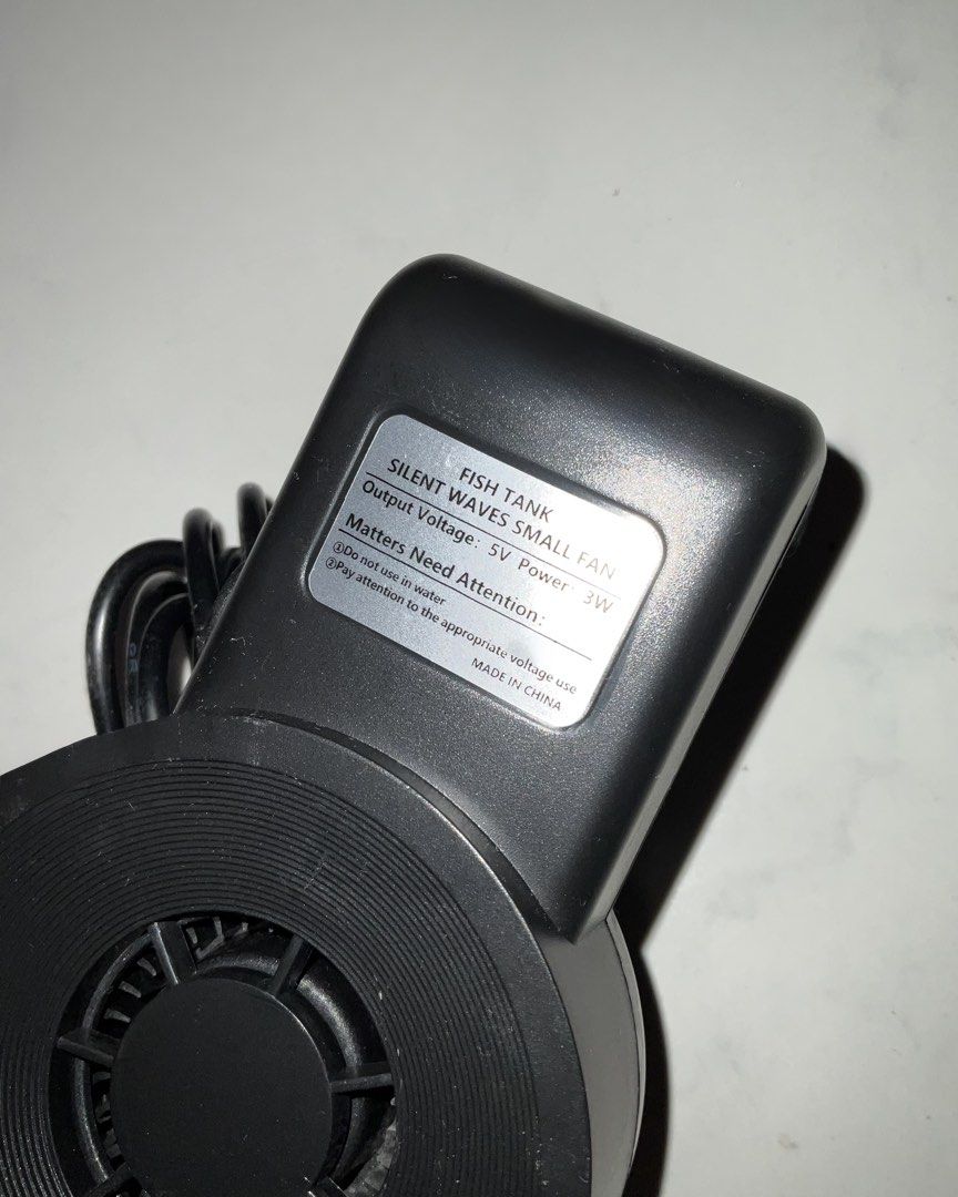 Silent Waves Small Fan for Fish Tank 5V 3W (Category: Fans) located in Pasig City. Submitted by joshua_listing (Listing ID 1467377426, Image 2). Description: - Color: Sleek black - Power: 5V, 3W efficient cooling - Design: Circular grill with attached power cable - Function: Effectively lowers aquarium water temperature - Important: Do not use in water; ensure appropriate voltage is used.