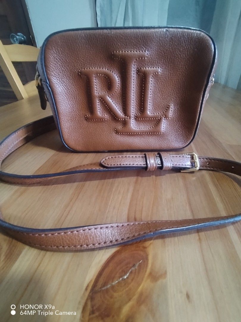 Sling Bag 7x 5 inches (Category: Cross-body Bags) located in Muntinlupa City. Submitted by arciagamaryann68 (Listing ID 1466203123, Image 1). Description: - Brand: Ralph Lauren (RL) - Color: Brown - Style: Compact sling bag / camera bag design - Material: Textured faux leather with embossed RL logo on front - Hardware: Gold-tone metal zippers and buckle details - Strap: Adjustable long strap for comfortable wear - Condition: pre loved used items 