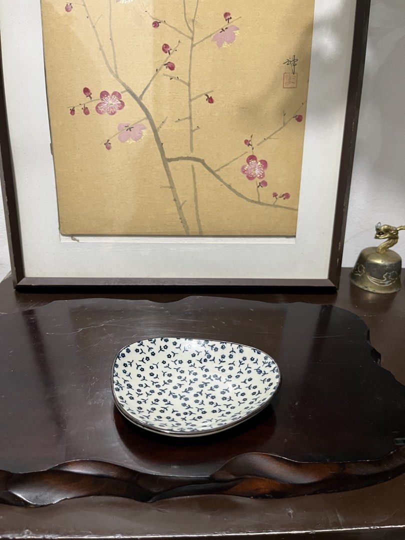 Small ceramic floral trinket dish (Category: Dinnerware & Cutlery) located in Taguig. Submitted by minmin_parker (Listing ID 1467473212, Image 1). Description: - Material: Smooth glossy ceramic with a metallic silver rim - Design: Asymmetrical rounded shape with all-over blue floral pattern - Usage: Ideal for holding rings, keys, and small bedside trinkets - Condition: Excellent, clean with no chips or cracks.