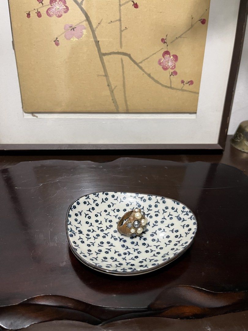 Small ceramic floral trinket dish (Category: Dinnerware & Cutlery) located in Taguig. Submitted by minmin_parker (Listing ID 1467473212, Image 3). Description: - Material: Smooth glossy ceramic with a metallic silver rim - Design: Asymmetrical rounded shape with all-over blue floral pattern - Usage: Ideal for holding rings, keys, and small bedside trinkets - Condition: Excellent, clean with no chips or cracks.