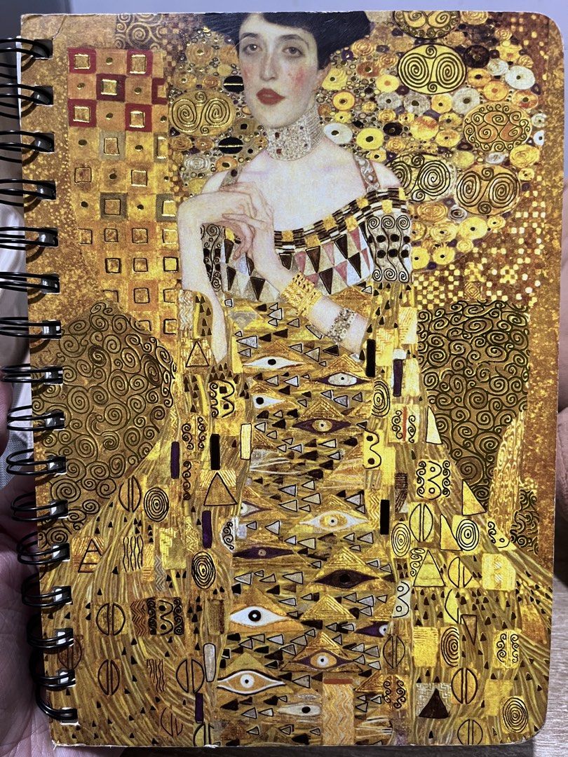 SPIRAL NOTEBOOK | Gustav Klimt Portrait of Adele Bloch-Bauer (Category: Art & Prints) located in Manila. Submitted by ilovethings17 (Listing ID 1467463516, Image 1). Description: - Iconic Gustav Klimt 'Portrait of Adele Bloch-Bauer I' artwork on the cover - Stunning full-front art print in rich, luxurious gold tones - Durable black wire binding on the left side - Versatile pages inside ideal for journaling, sketching, or daily note-taking - Perfe