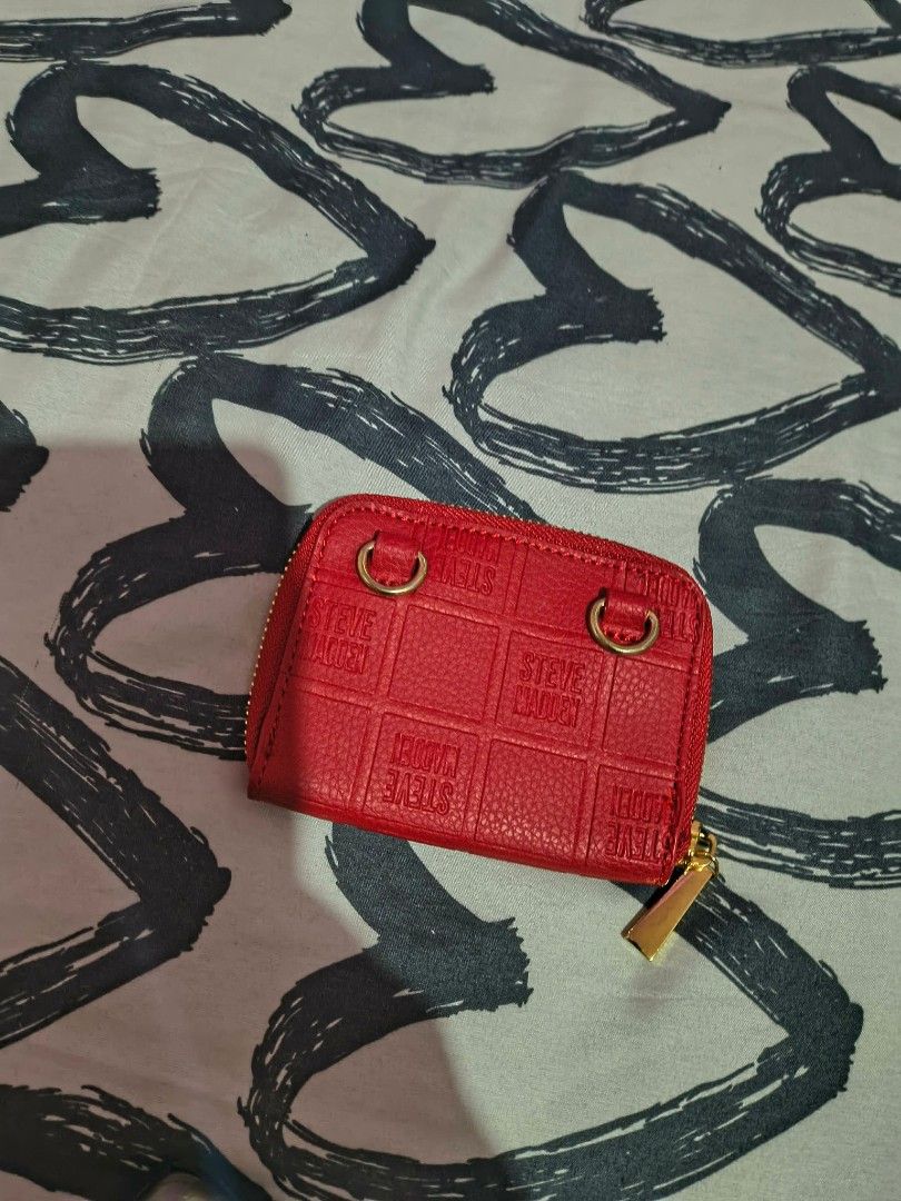 Steve Madden Red Zip Around Wallet (Category: Wallets & Card holders) located in Cavite. Submitted by mahthriftshop (Listing ID 1467382061, Image 3). Description: - Brand: Steve Madden - Color: Bright red with debossed logo grid pattern - Hardware: Gold-tone with plastic protector still on the front logo badge - Closure: Secure zip-around - Interior: Multiple card slots and spacious accordion compartments - Special Feature: Two metal rings on the