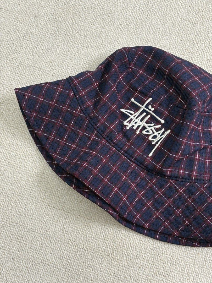 Stussy Plaid Bucket Hat (Category: Caps & Hats) located in Manila. Submitted by porma.market (Listing ID 1467404194, Image 1). Description: - Brand: Stussy - Design: Navy and burgundy plaid - Logo: Iconic embroidered white signature logo on front - Interior: Black lining with official branded inner tag - Fit: Structured brim, comfortable for everyday wear - Style: Classic streetwear essential.