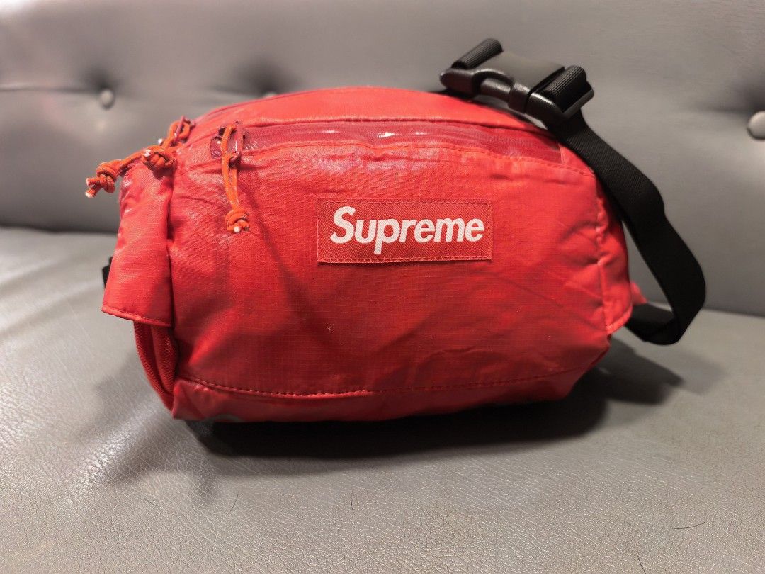 Supreme Red Waist Bag (Category: Belt bags, Clutches and Pouches) located in Cagayan de Oro. Submitted by pootx (Listing ID 1467518410, Image 1). Description: - Authentic Supreme waist bag in striking bright red - Features the classic box logo on the front and reflective branding along the bottom - Multiple zipped compartments equipped with easy-pull toggles - Secure interior lined in red fabric with an extra slip pocket - Adjustable black straps