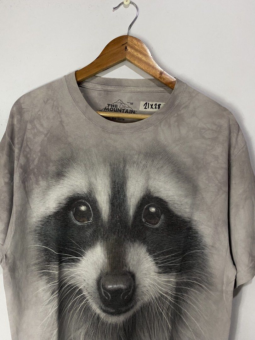 THE MOUNTAIN TSHIRT (Category: Tshirts & Polo Shirts ) located in Jaen. Submitted by oshimamark58418 (Listing ID 1467534481, Image 2). Description: - Brand: The Mountain - Design: Realistic large raccoon face graphic print with copyright 2013 Vincent Hie - Color: Vintage grey acid-wash style - Material: 100% Cotton - Size: Tagged M, fits like Large (Measured approx. 21 inches width x 28 inches length) - Condition: Excellent pre-owned condition - 
