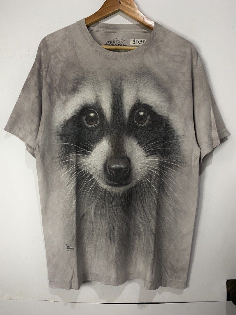 THE MOUNTAIN TSHIRT (Category: Tshirts & Polo Shirts ) located in Jaen. Submitted by oshimamark58418 (Listing ID 1467534481, Image 1). Description: - Brand: The Mountain - Design: Realistic large raccoon face graphic print with copyright 2013 Vincent Hie - Color: Vintage grey acid-wash style - Material: 100% Cotton - Size: Tagged M, fits like Large (Measured approx. 21 inches width x 28 inches length) - Condition: Excellent pre-owned condition - 