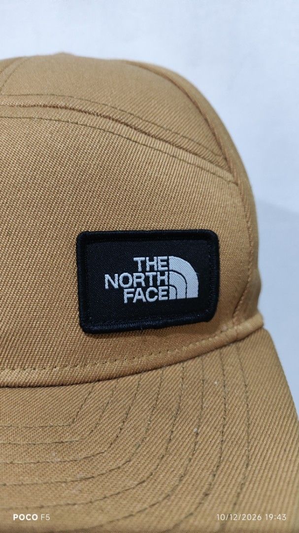 The North Face Brown Snapback Cap (Category: Caps & Hats) located in Quezon City. Submitted by ralphralph (Listing ID 1467498995, Image 2). Description: - Brand: The North Face - Style: Classic 5-panel snapback cap with a flat brim - Color: Brown - Details: Woven TNF logo patch on the front right - Fit: Adjustable plastic snap closure in the back - Condition: Clean fabric, sturdy construction, ready to wear.