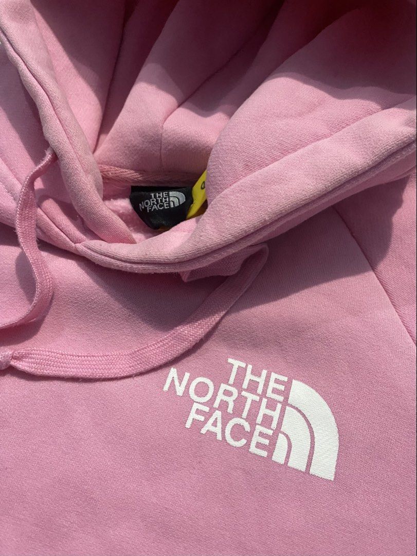 The North Face Pink Graphic Pullover Hoodie (Category: Coats, Jackets and Outerwear) located in Manila. Submitted by jerms.thriftah (Listing ID 1467399566, Image 3). Description: - Brand: The North Face - Color: Pink with white chest logo - Design: Large mountain graphic and "Never Stop Exploring" text on the back - Features: Adjustable braided drawstrings, kangaroo pocket, and soft fleece lining - Fit: Standard fit - Condition: Excellent, pre-lo