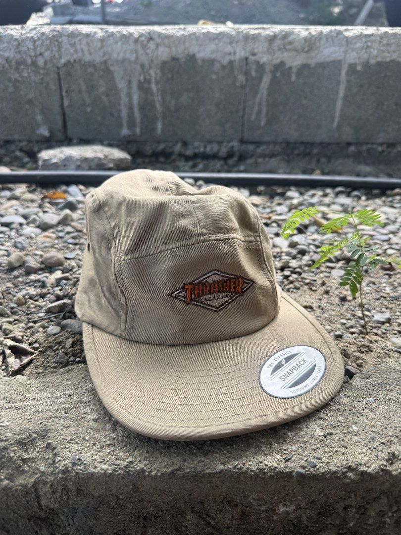 Thrasher Magazine 5-Panel Snapback Hat Tan (Category: Caps & Hats) located in Burgos, Ilocos Norte. Submitted by copthrift (Listing ID 1467371599, Image 1). Description: - Brand: Thrasher Magazine (The Classics by Yupoong) - Style: 5-panel flat brim snapback cap - Color: Tan - Details: Embroidered diamond logo patch on front, original sticker still on brim - Material: 100% cotton, made in Vietnam - Fit: Adjustable strap closure with side metal ey