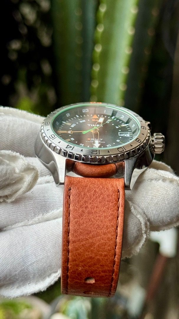 Timex GMT Watch with Leather Strap (Category: Men's Watches) located in Manila. Submitted by junjun12356 (Listing ID 1467573827, Image 3). Description: - Brand/Model: Timex GMT Watch - Dial: Grey with vibrant orange and green accents - Case & Bezel: Stainless steel case with dual time zone bezel - Features: Date window at 3 o'clock position, keeps accurate time - Strap: Brown leather strap with secure buckle closure - Condition: 9.5/10.