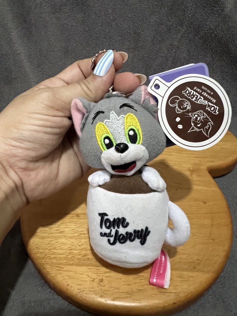Tom and Jerry Plush Coffee Cup Keychain (Category: Plushies & Soft Toys) located in Las Pinas. Submitted by maple0305 (Listing ID 1467401106, Image 1). Description: - Adorable Tom the cat plush toy tucked inside a white coffee cup - Features an embroidered Tom and Jerry logo on the mug - Comes with a ball chain, perfect for hanging on bags or keys - Includes original brand tags, 100% authentic - Great collectible accessory or gift for fans.