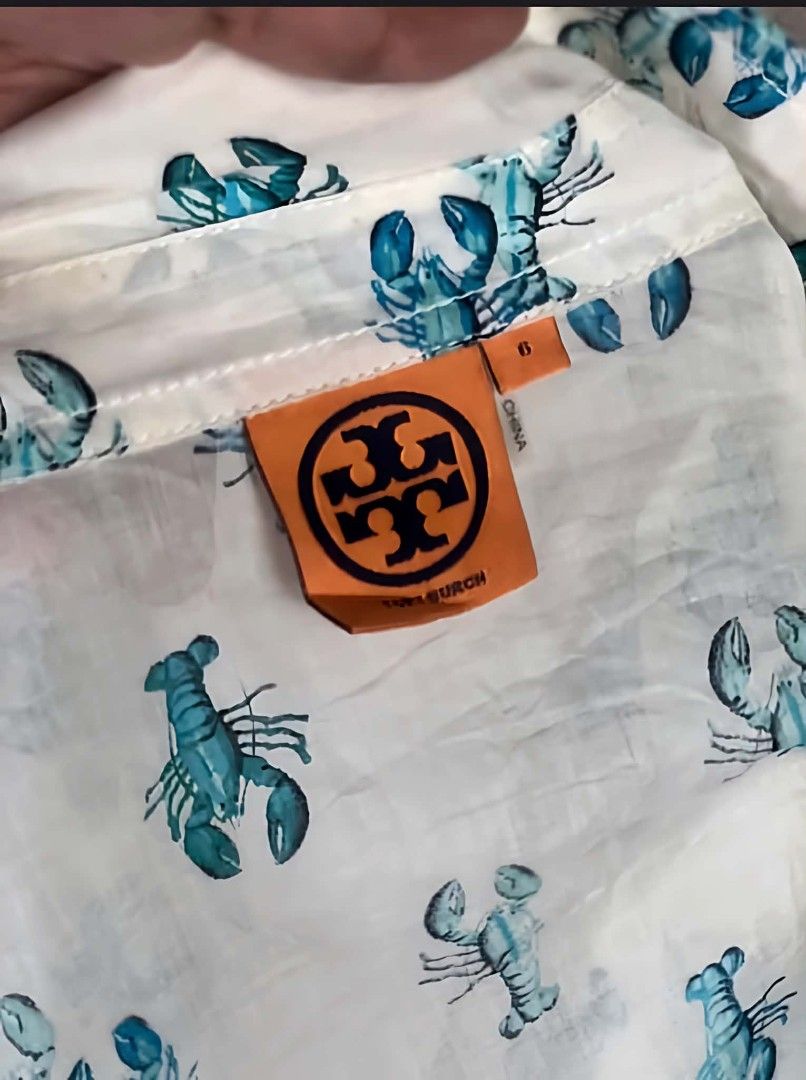 Tory Burch Blue Lobster Print Button-Down Blouse Size 6 (Category: Blouses) located in Pasig City. Submitted by dertah (Listing ID 1467510622, Image 2). Description: - Brand: Tory Burch - Style: Long-sleeve button-down shirt with playful blue lobster print - Size: 6 (Orange brand neck label) - Features: Classic collar neckline, two buttoned chest pockets, roll-tab sleeves secured with green buttons - Material: Lightweight, breathable cotton - Con