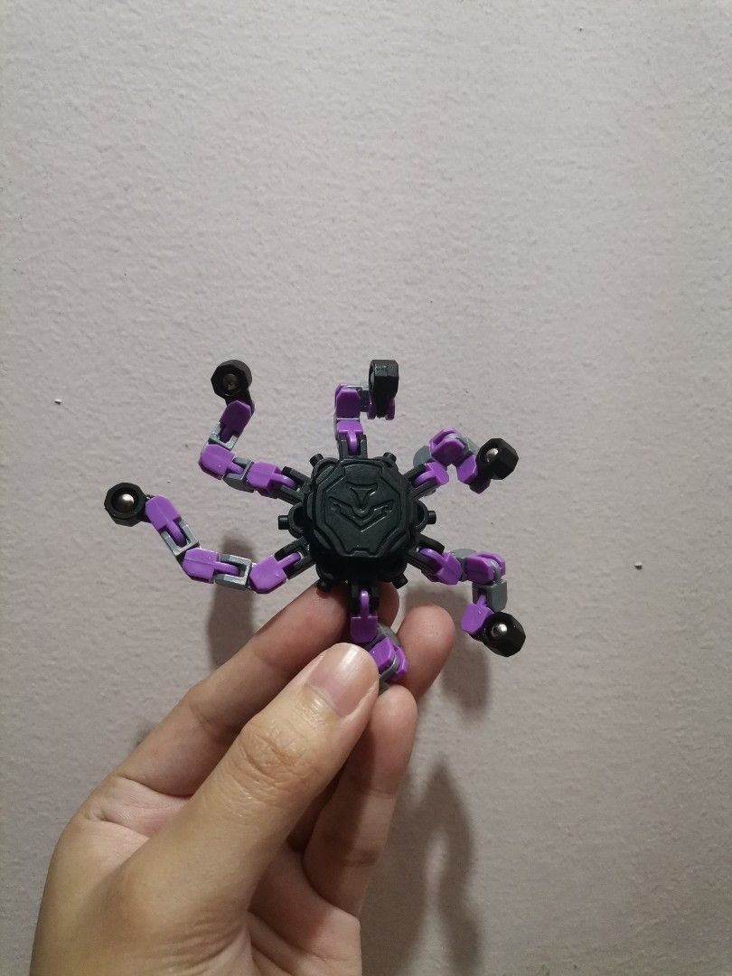 Transformable Multi-jointed Fidget Toy Spider Spinner (Category: Action & Battle Toys) located in Makati City. Submitted by kookybearsstuff (Listing ID 1467496533, Image 2). Description: - Purple and black transformable fidget toy - 6 flexible, articulated legs that bend into various shapes - Central hub with gear design on one side and textured emblem on the other - Smooth movement at all joints, perfect for stress relief - Clean condition and w