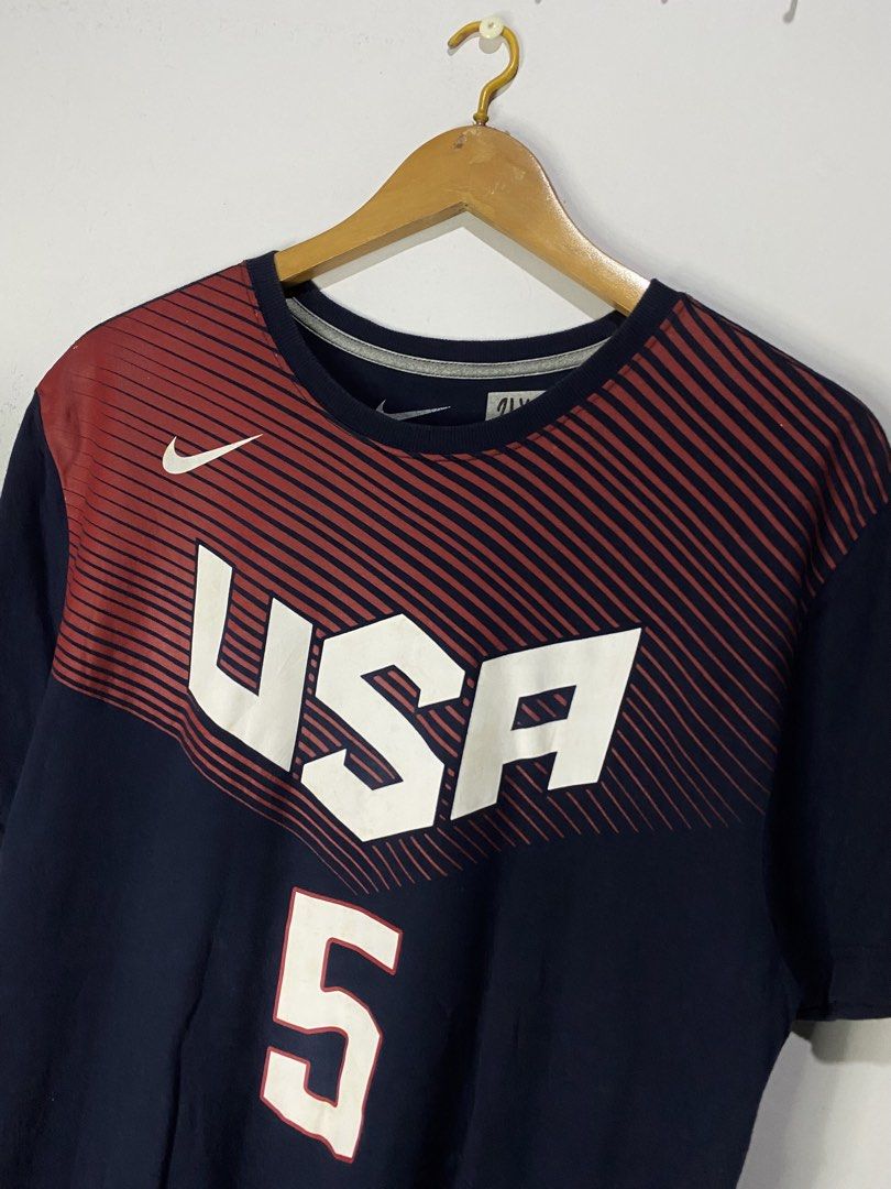 TSHIRT (Category: Tshirts & Polo Shirts ) located in Jaen. Submitted by oshimamark58418 (Listing ID 1467515958, Image 3). Description: - Brand: Nike - Player/Team: Team USA Kevin Durant (#5) - Color: Navy blue with red striped shoulder/chest design - Size: XL Regular Fit (approx. 21 x 30 inches) - Features large USA and number 5 graphics on front, DURANT 5 on back - Comfortable cotton-blend material, ideal for sports or daily casual wear.