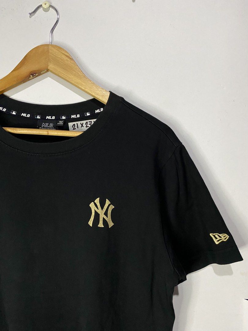 MLB TSHIRT (Category: Tshirts & Polo Shirts ) located in Jaen. Submitted by oshimamark58418 (Listing ID 1467524686, Image 3). Description: - Brand: MLB (New York Yankees) - Color: Black with Gold Print - Size: Medium (approx. 21" x 27") - Design: Small gold NY logo on front, large gold Yankees logo on back, New Era sleeve embroidery - Condition: Excellent pre-loved condition - Material: Comfortable cotton, ideal for everyday casual wear.