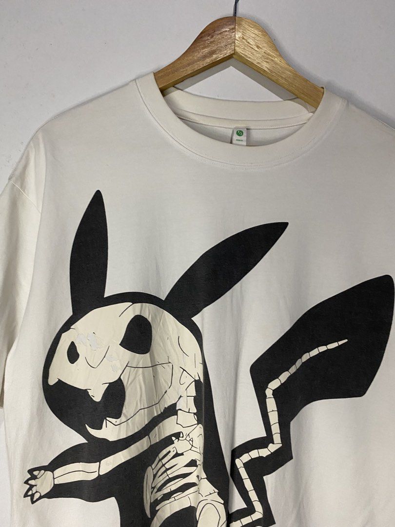 TSHIRT (Category: Tshirts & Polo Shirts ) located in Jaen. Submitted by oshimamark58418 (Listing ID 1467525033, Image 3). Description: - Brand: FANJI - Size: L - Color: White - Design: Skeleton Pikachu graphic on front, 'GOOD BANKS' lettering on back - Details: Features a branded 'R / Aspire to Guaranteed' patch near the hem - Style: Streetwear, casual, anime-inspired - Condition: Good pre-owned condition.