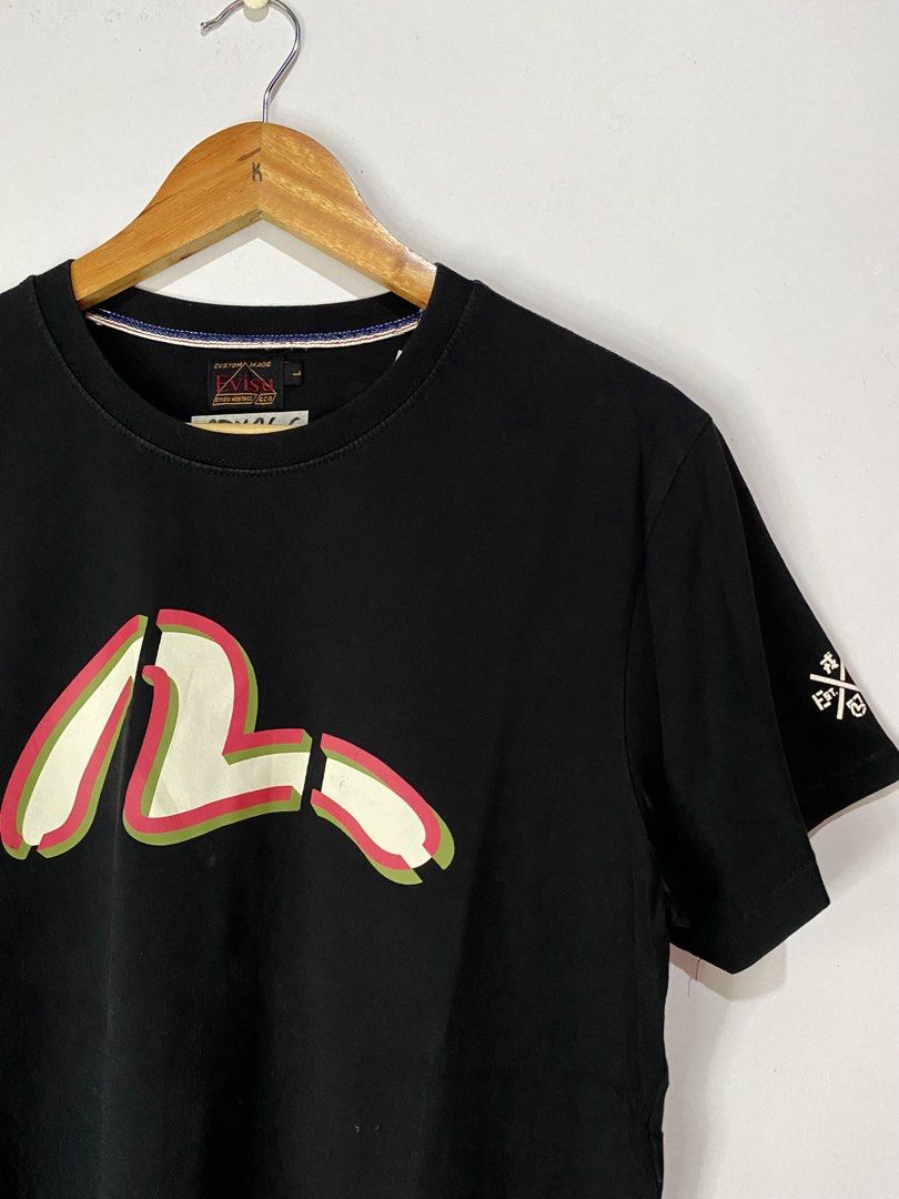 EVISU TSHIRT (Category: Tshirts & Polo Shirts ) located in Jaen. Submitted by oshimamark58418 (Listing ID 1467527913, Image 3). Description: - Brand: Evisu - Color: Black - Size: M (tagged L, approx. 20x26 inches) - Condition: Excellent pre-loved condition (Layered condition: 4) - Features: Multi-color front logo, bold back graphic with 'Before Anyone Did Anything' & 'EV-91 Evisu Force' lettering, sleeve print, and woven brand patches at the hem 