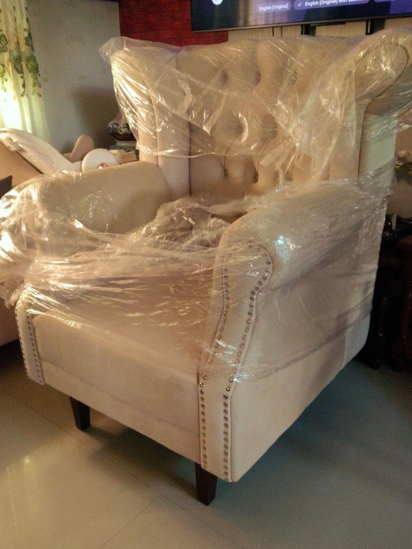 Tufted Wingback Armchair with Nailhead Trim (Category: Sofas) located in Manila. Submitted by gigicore (Listing ID 1467406424, Image 1). Description: - Style: Elegant tufted wingback armchair - Color & Material: Light cream fabric upholstery with dark wooden legs - Design Details: Deep button tufting on high backrest and rolled arms with silver nailhead trim - Condition: Brand new-like, wrapped in protective plastic to ensure upholstery stays cle