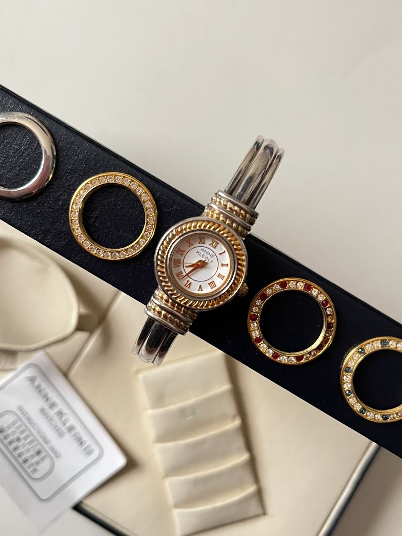 Two Toned Open Cuff Anne Klein Watch with Interchangeable Bezels (Category: Women's Watches) located in Imus. Submitted by 143vintage (Listing ID 1467413027, Image 2). Description: Switch up your style in seconds with this gorgeous vintage Anne Klein II interchangeable bezel watch set! This stunning ladies' dress wristwatch features a classic round face with a silver cuff bracelet, complete with five easily swappable, colorful bezels—including mu