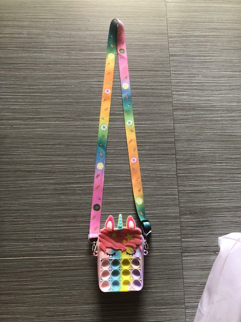 Unicorn Pop It sling bag (Category: Babies & Kids Fashion) located in Cavite. Submitted by ai__chang (Listing ID 1467405997, Image 2). Description: - Cute pastel unicorn design in vibrant rainbow shades - Built-in pop-it bubble toy on the front for endless fun - Made from durable, flexible, and easy-to-clean silicone - Long, adjustable strap featuring fun ice cream and donut prints - Perfect size for carrying small daily essentials - Great gift i