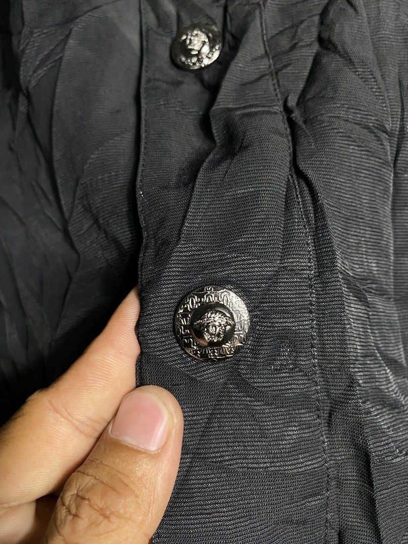 Versace Black Casual Jacket (Category: Coats, Jackets and Outerwear) located in Cabanatuan. Submitted by brightwater-2083 (Listing ID 1467520552, Image 2). Description: Black Versace jacket with button closure and front pockets. Textured fabric with inner lining. Branded silver-tone metal buttons featuring the Medusa head motif. Tag on the inside collar shows Versace branding and care instructions. Width 22.5 Length 29.5.