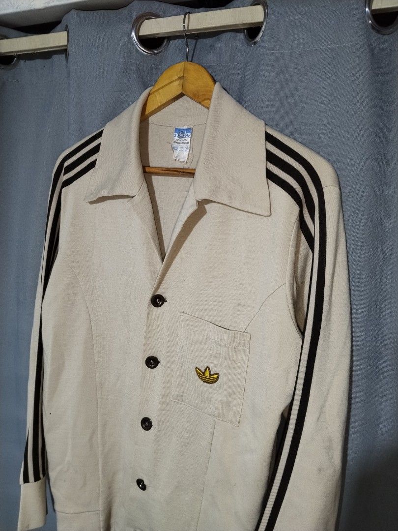 Vintage 70s Adidas Schwan Metal Button Jacket (Category: Coats, Jackets and Outerwear) located in Pasig City. Submitted by loveforlux_2025 (Listing ID 1467408771, Image 3). Description: - Brand: Adidas - rare find - Style: Vintage cardigan with dark stripes on sleeves - Color: Beige - Details: Classic pointed lapel collar, button-up front, single chest pocket with embroidered gold trefoil logo, adjustable button cuffs - Condition: Retro piece wit