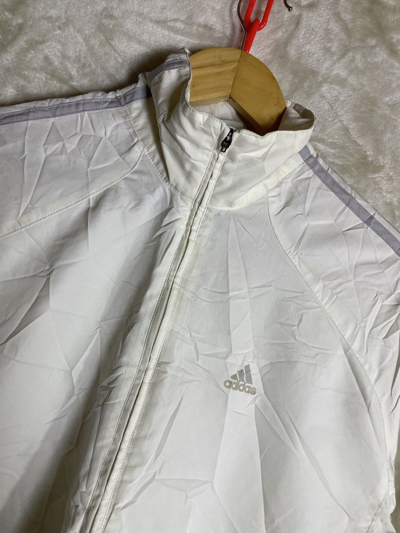 Vintage Adidas White Track Jacket Windbreaker (Category: Coats, Jackets and Outerwear) located in Molave. Submitted by charlesthrifter (Listing ID 1467366586, Image 2). Description: - Color: Clean white with iconic grey stripes down both sleeves - Design: High collar, half-zip front closure, and dual zipper waist pockets - Material: Lightweight and comfortable, perfect for workouts or casual streetwear - Authenticity: Features the classic blue Ad