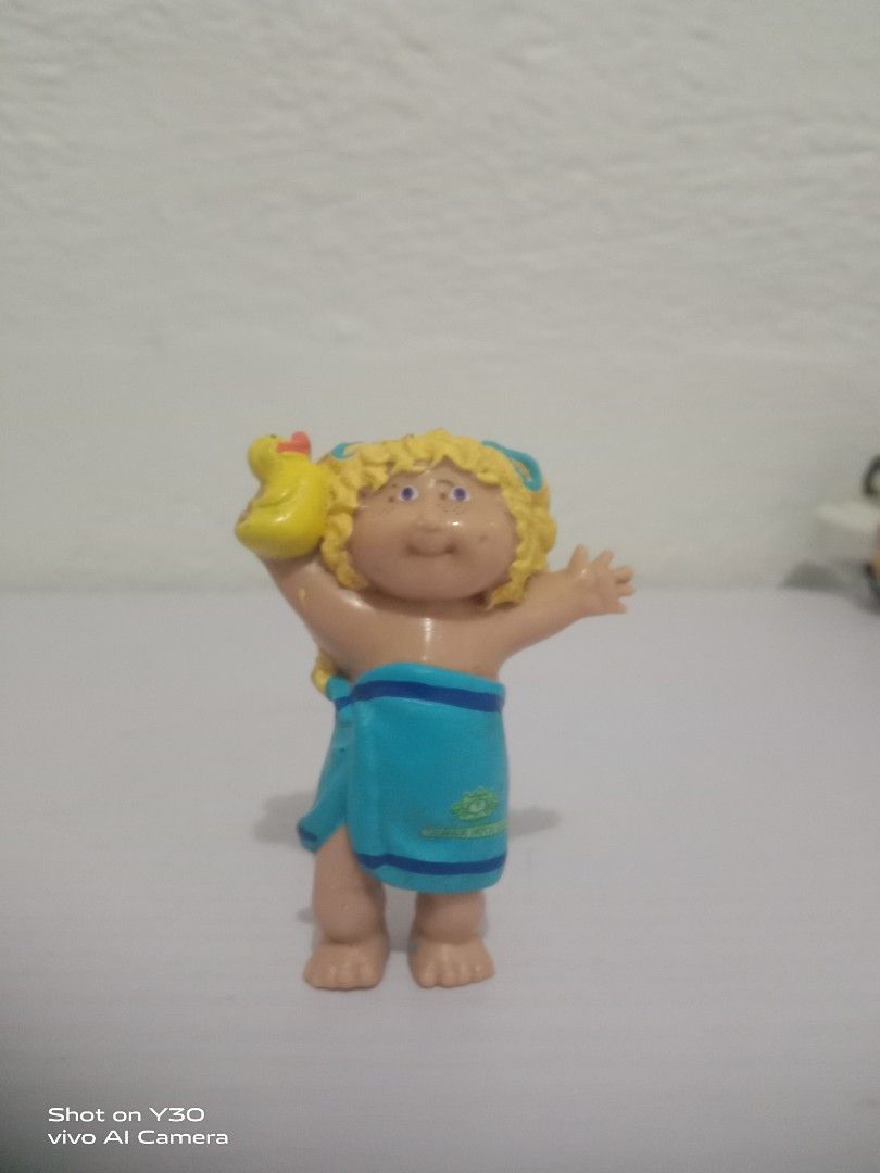 Vintage Cabbage Patch Kids Bath Time Figurine (Category: Figurines & Statues) located in Orani. Submitted by rodel1991 (Listing ID 1467374892, Image 1). Description: - Authentic Cabbage Patch Kids collectible figurine - Blonde hair styled in pigtails with cute blue hair ties - Adorable design wearing a blue towel wrap and holding a yellow rubber duck - Features classic chubby cheeks and detailed facial expressions - Standing pose with arms raised